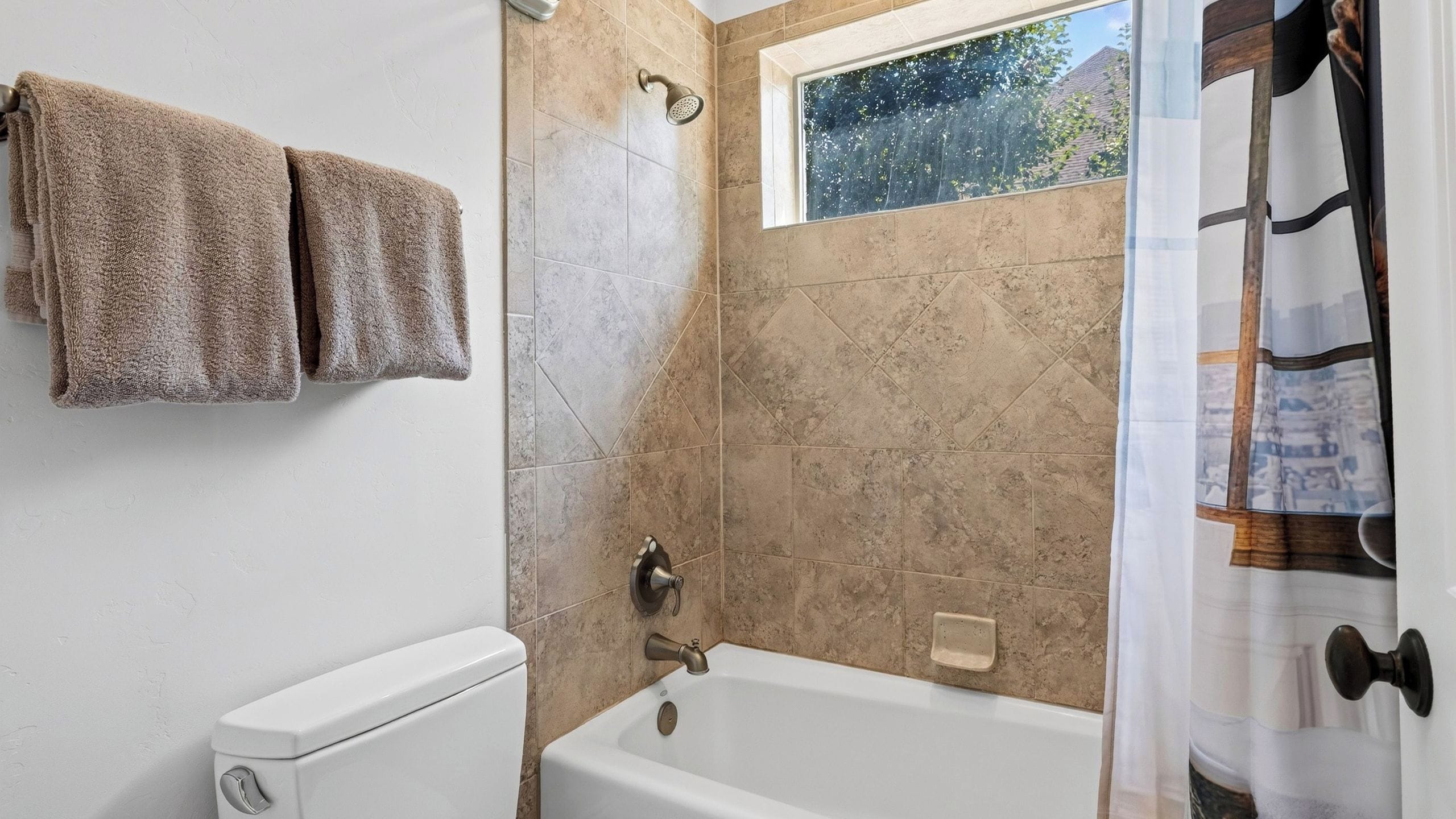 A bathroom with a bathtub, a showerhead, and a window.