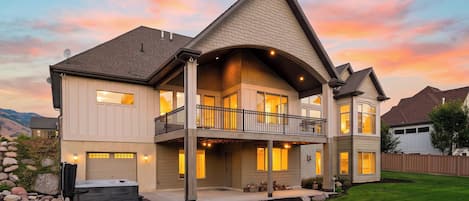 A two-story house with a balcony, large windows, and a well-maintained lawn.
