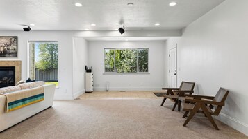 A spacious living room with a sofa, a dining table with chairs, and a large window.