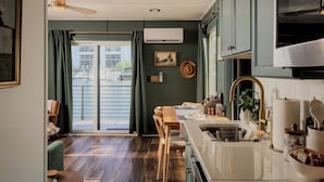 A kitchen with a view to a water body, wooden flooring, and a dining area with a table and chairs.