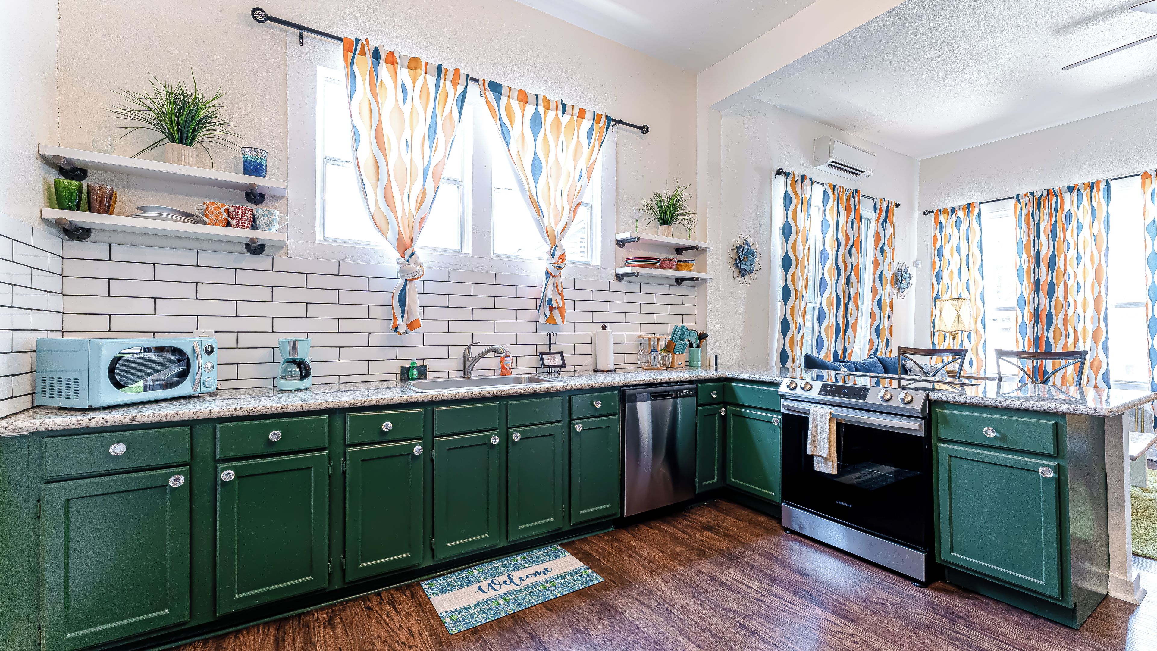 A kitchen with green cabinets, a microwave, a coffee maker, and a stove.