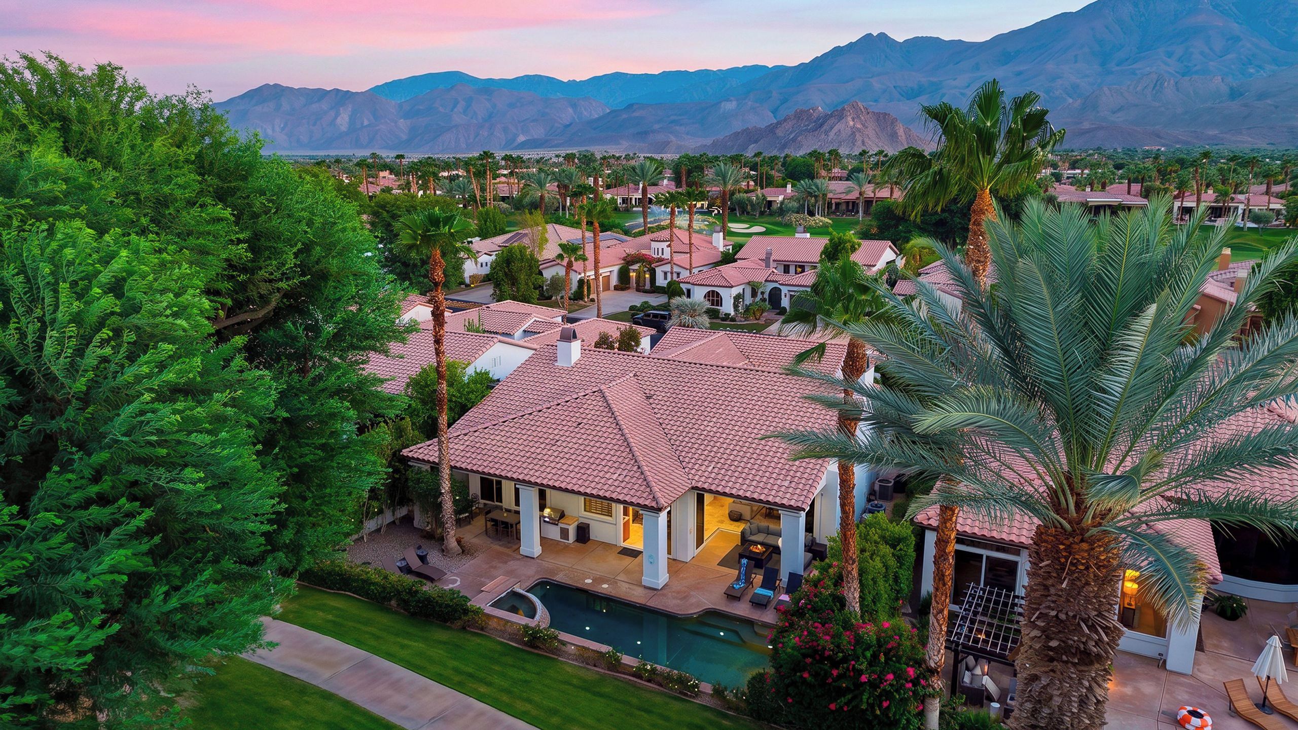 A residential area with houses, a swimming pool, and mountains in the background.