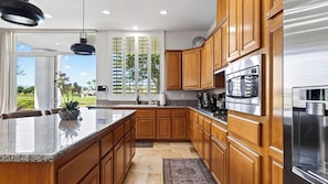 A modern kitchen with wooden cabinets, stainless steel appliances, and a large island.