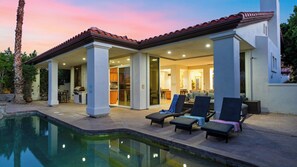 A modern house with a pool, outdoor seating, and a covered patio area.