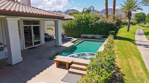 A residential property with a swimming pool, patio seating, and a view of mountains.