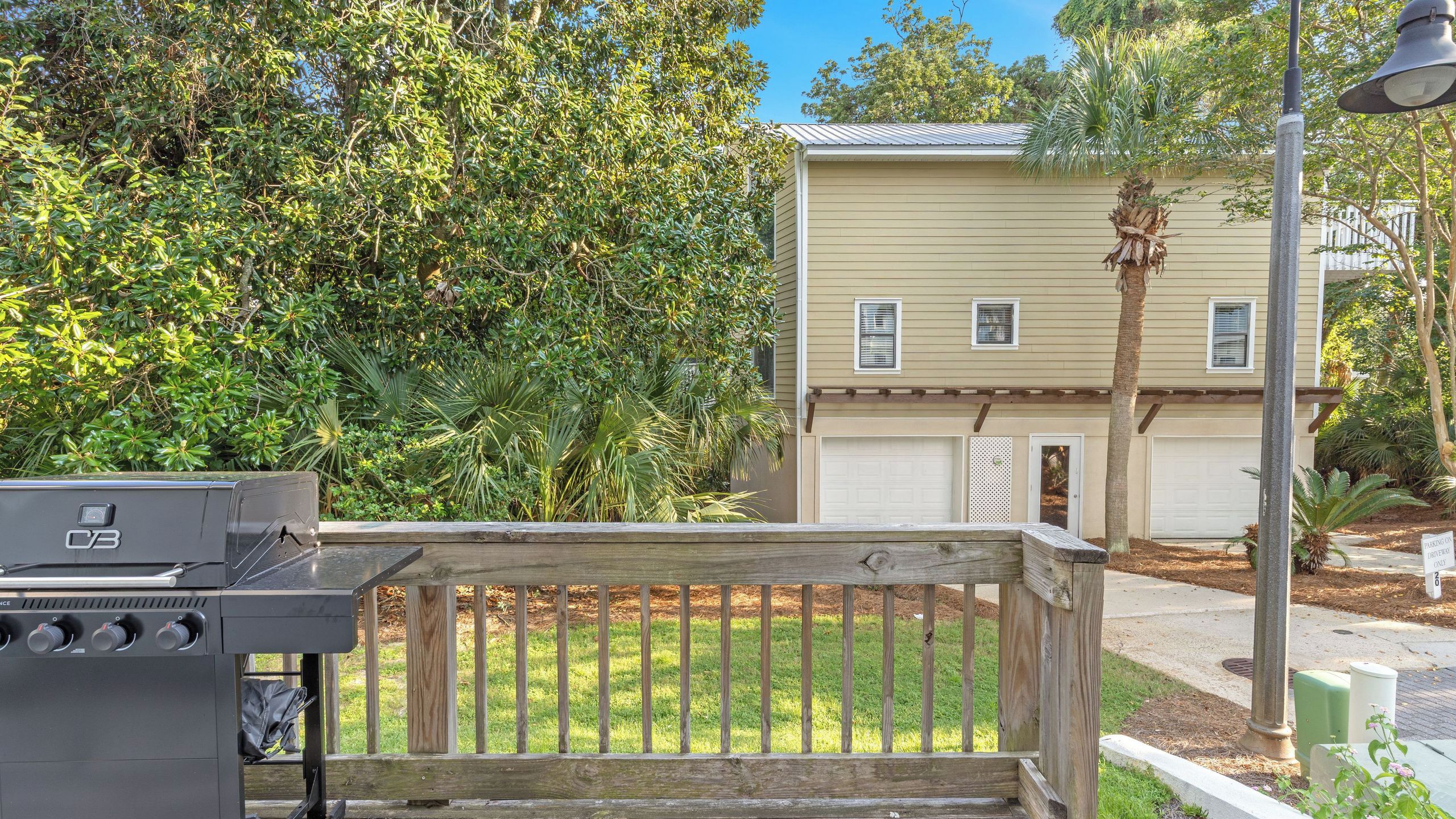 A residential area with a wooden deck, a barbecue grill, and a house with a garage.