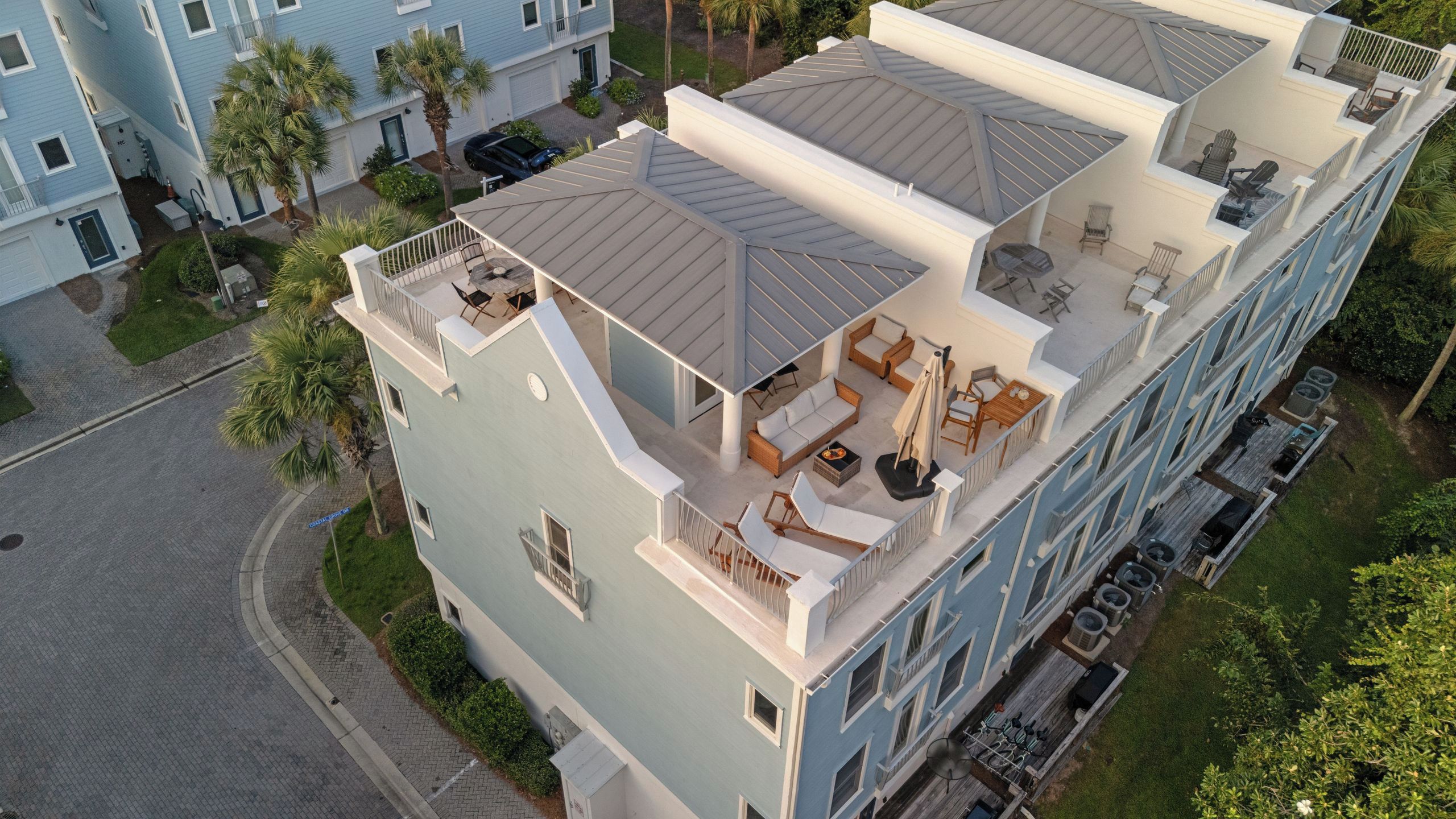 A multi-story hotel with a rooftop terrace featuring outdoor seating and a pool.