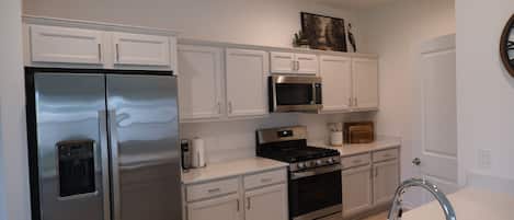 A modern kitchen with white cabinetry, stainless steel appliances, and a built-in microwave.