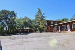 A two-story building with a gravel driveway and trees in the background.