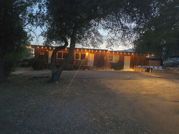 A rustic building with a wooden exterior, a paved driveway, and a small garden area.