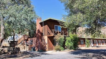 A rustic wooden building with a staircase leading to a second level, surrounded by trees.
