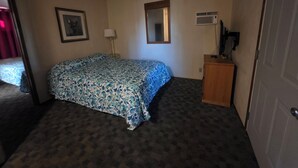 Quarto de hotel com cama, mesa de cabeceira, luminária, espelho e ar condicionado na parede.