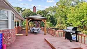 En uteplats med ett takbeklätt sittområde, en grill och en mur av tegelsten.
