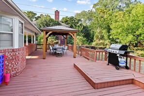 Eine Terrasse mit überdachter Sitzgruppe, einem Grill und einer Ziegelwand.