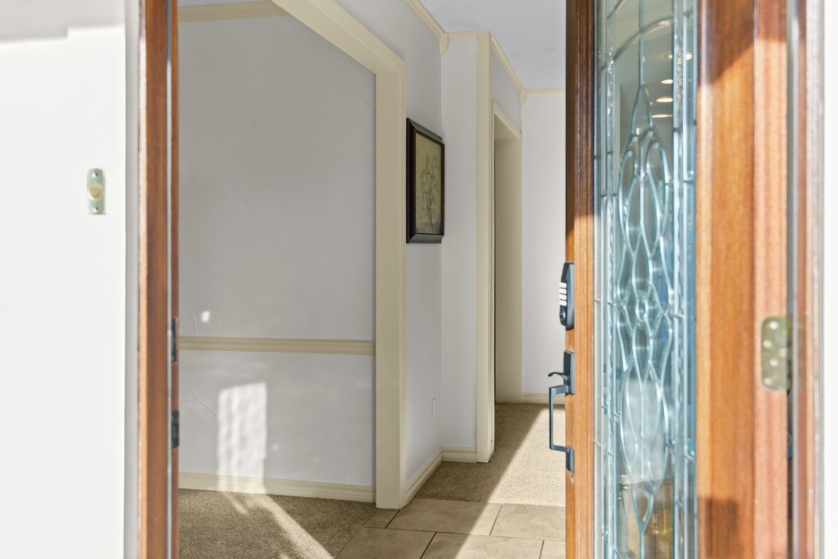 A hallway with a wooden door and a glass door leading to another room.
