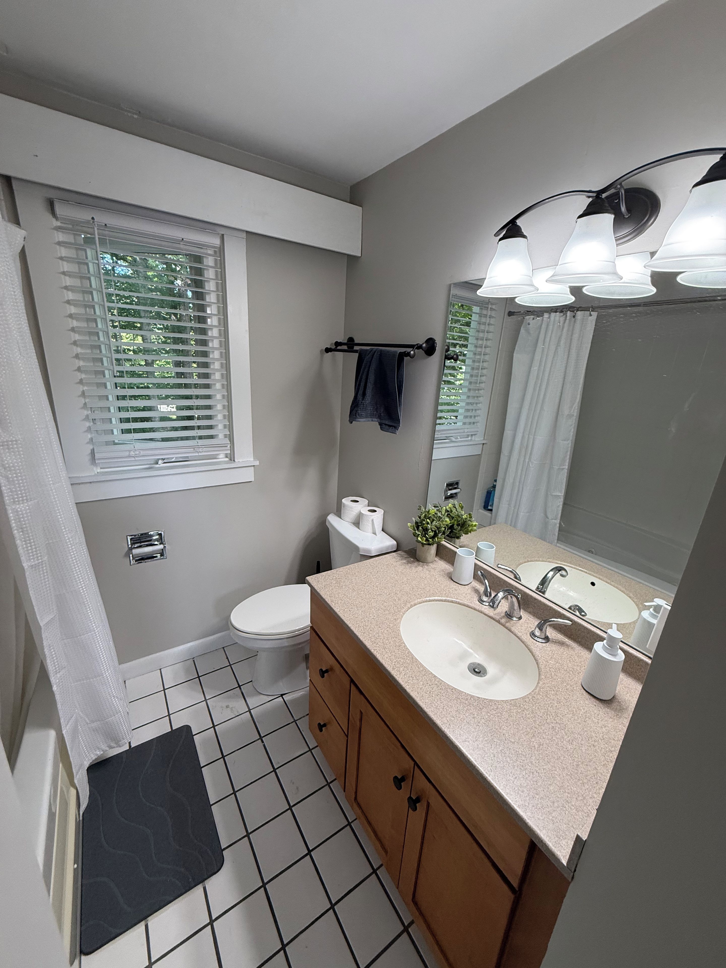 A bathroom with a toilet, sink, mirror, and towel rack.