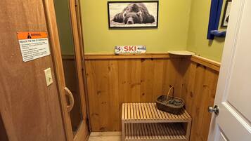 A small, narrow room with wooden walls and a wooden bench. There is a sign on the wall and a picture of a bear.