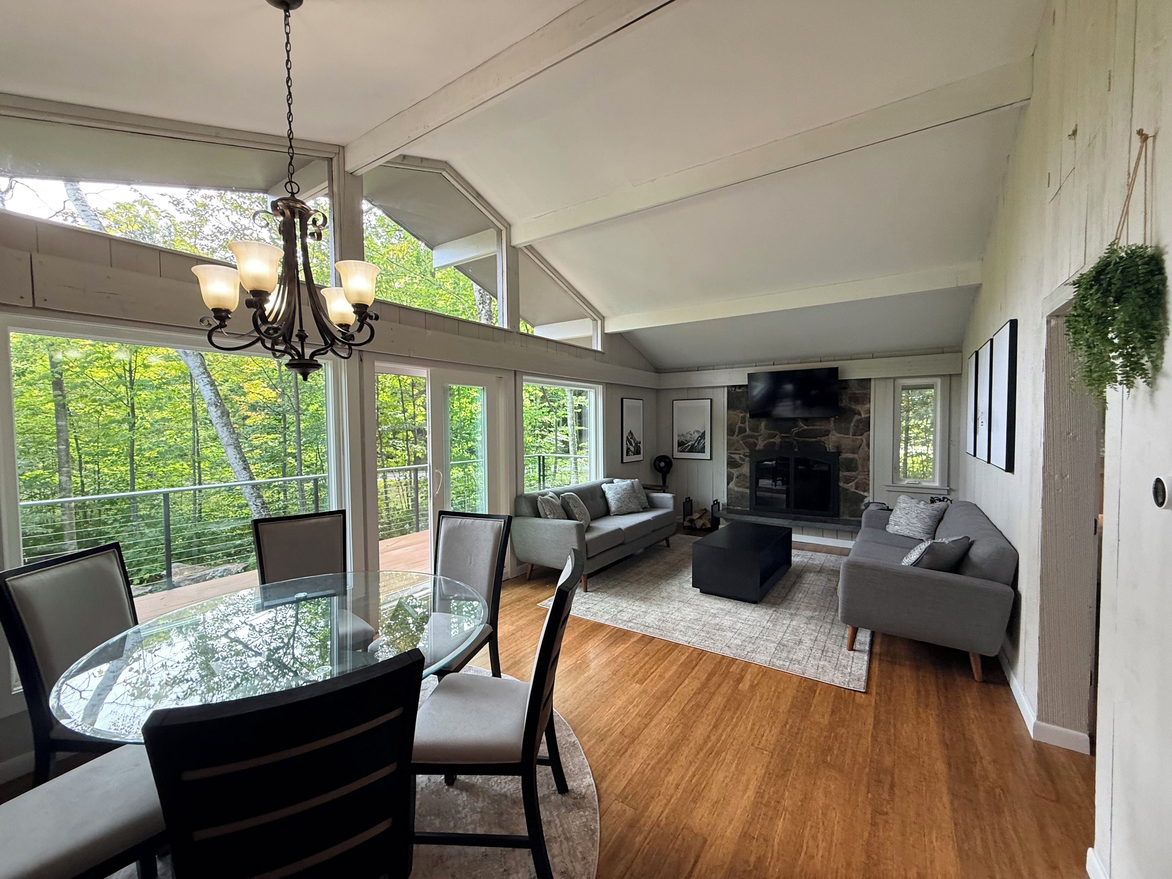 A spacious living area with a glass dining table, sofas, and a fireplace.