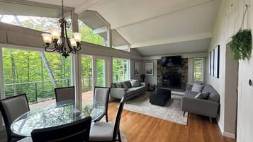 A spacious living area with a glass dining table, sofas, and a fireplace.