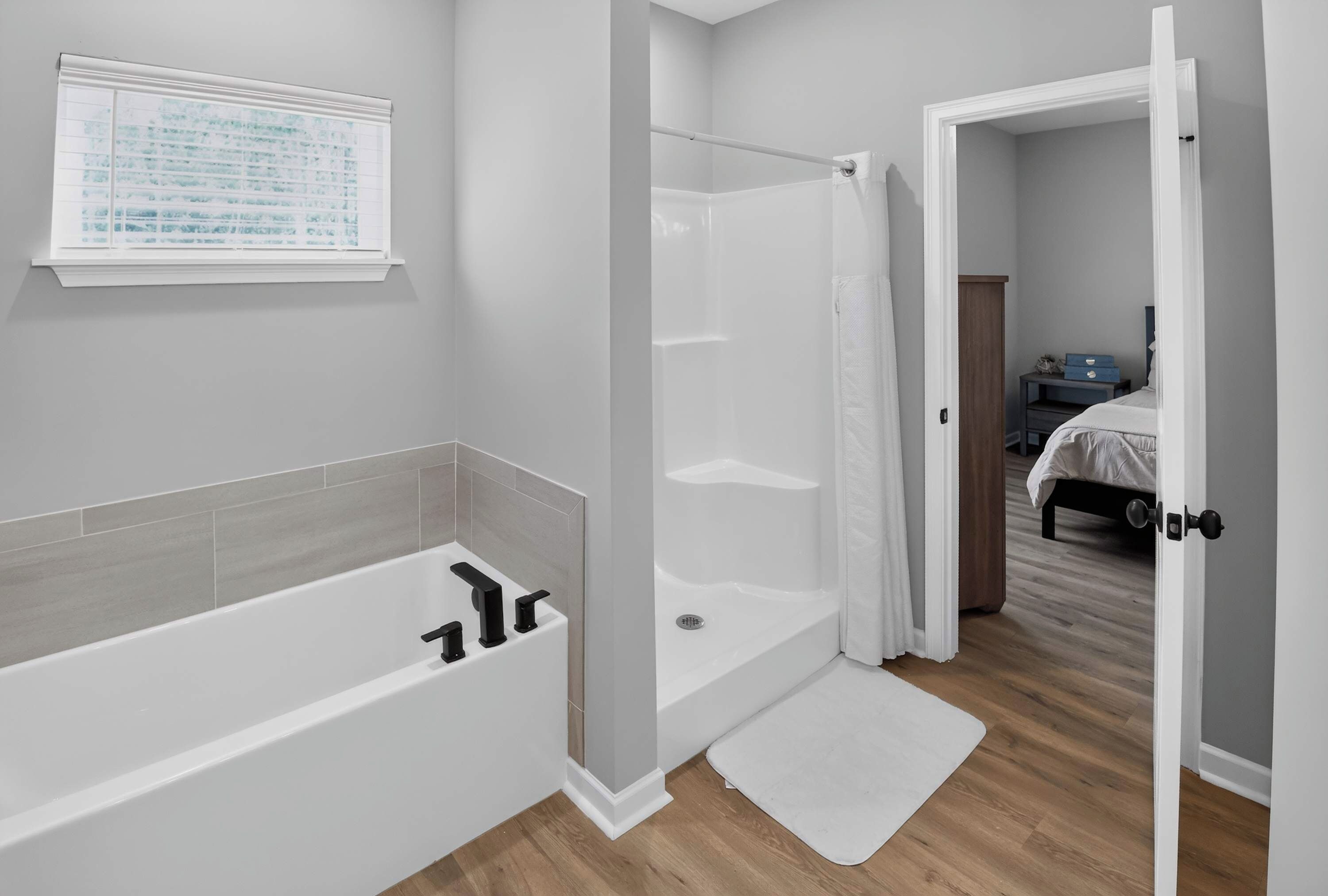 A modern bathroom with a bathtub, shower, and a window with a view.