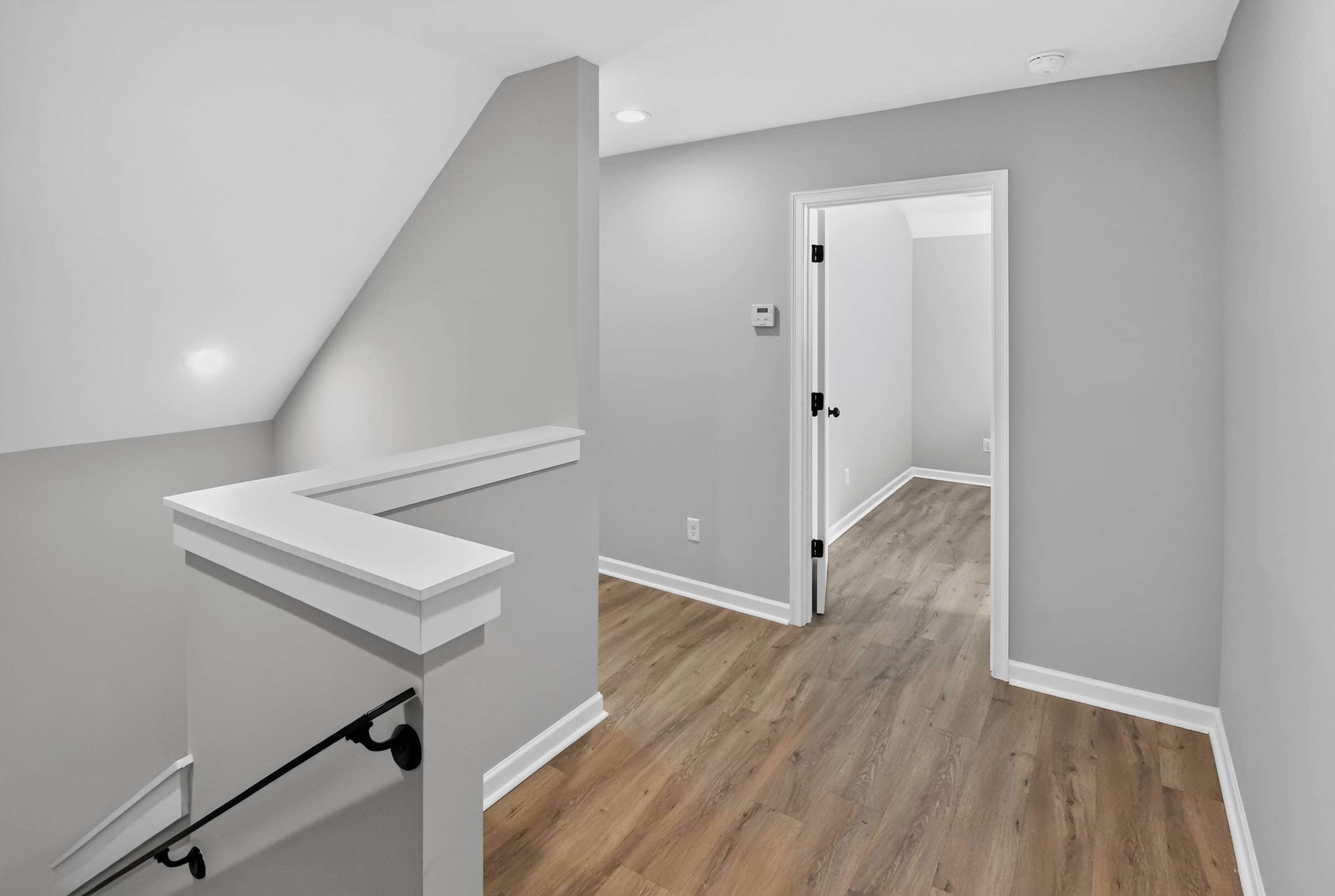 A modern interior with a staircase, a door leading to another room, and a light switch on the wall.
