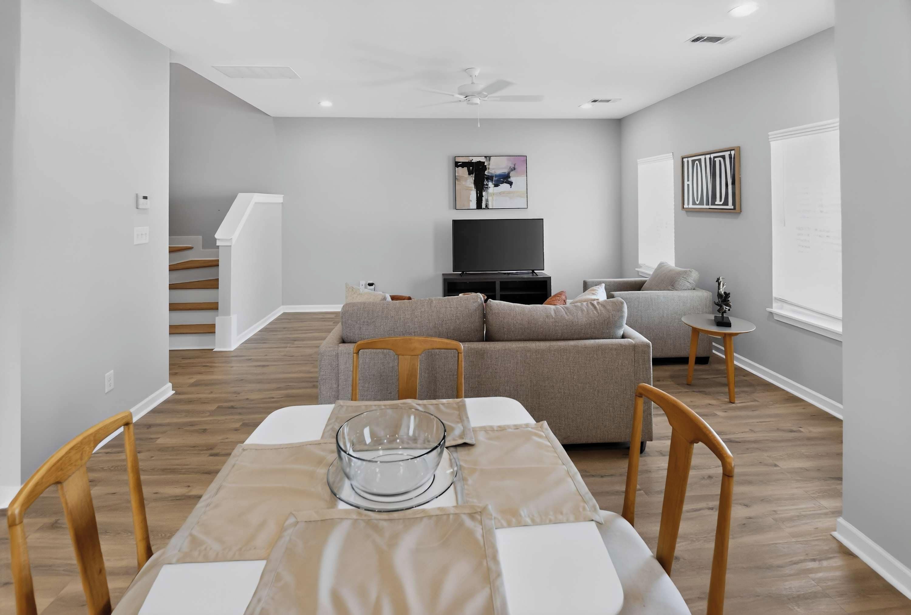 Una sala moderna con una mesa de comedor, sofás y un televisor de pantalla plana.