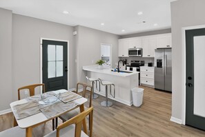 A modern kitchen with white cabinets, stainless steel appliances, and a central island with bar stools.