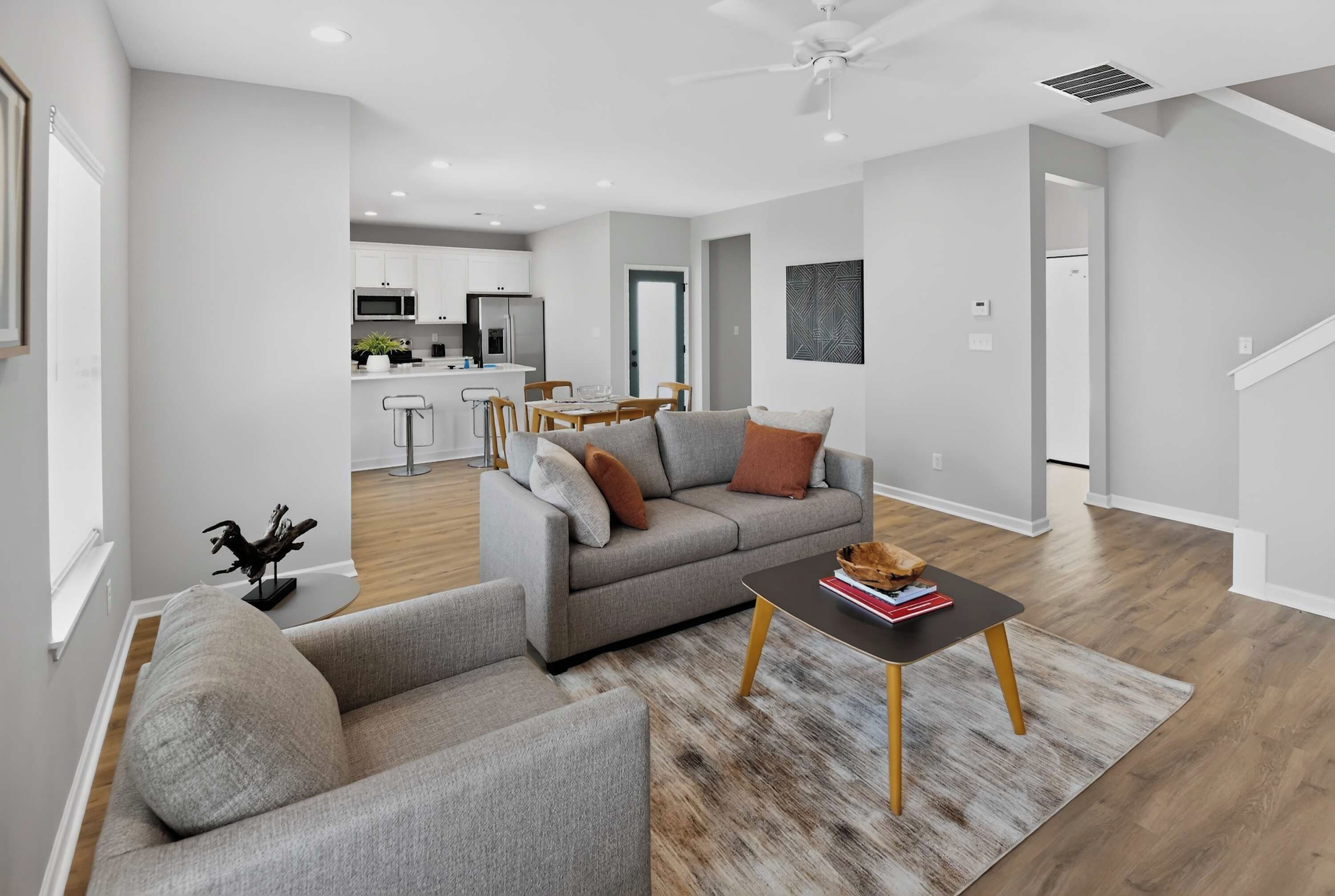 A modern living room with a grey sofa, a coffee table, and a dining area in the background.