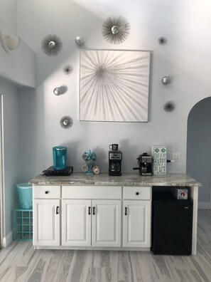A kitchen with white cabinets, a coffee maker, a toaster, and a refrigerator. - Cape Escape Oversized Pool Home in coveted Cape Harbor area of Cape Coral (Cape Coral)