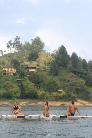 Three individuals on a watercraft with a hilly landscape and buildings in the background. - Violet - with terrace, hammock (Guatapé)