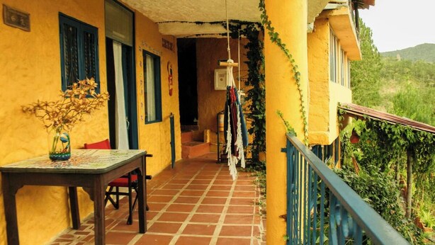 A yellow building with a tiled patio, a table with chairs, and a hanging clothesline. - Violet - with terrace, hammock (Guatapé)
