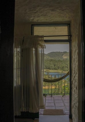 A room with a view of a landscape through a large window, a hammock, and a curtain. - Violet - with terrace, hammock (Guatapé)