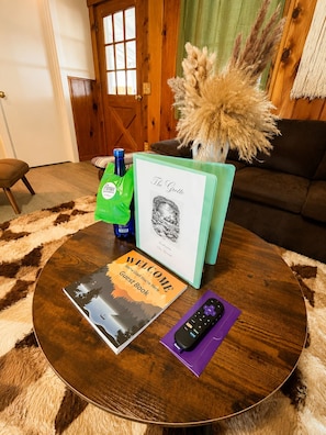 A round wooden coffee table with a welcome book, a remote control, and a decorative vase with dried plants. - Kernville Center/Walk/2 Hot Tubs/2 Units/Mini Golf (Kernville)