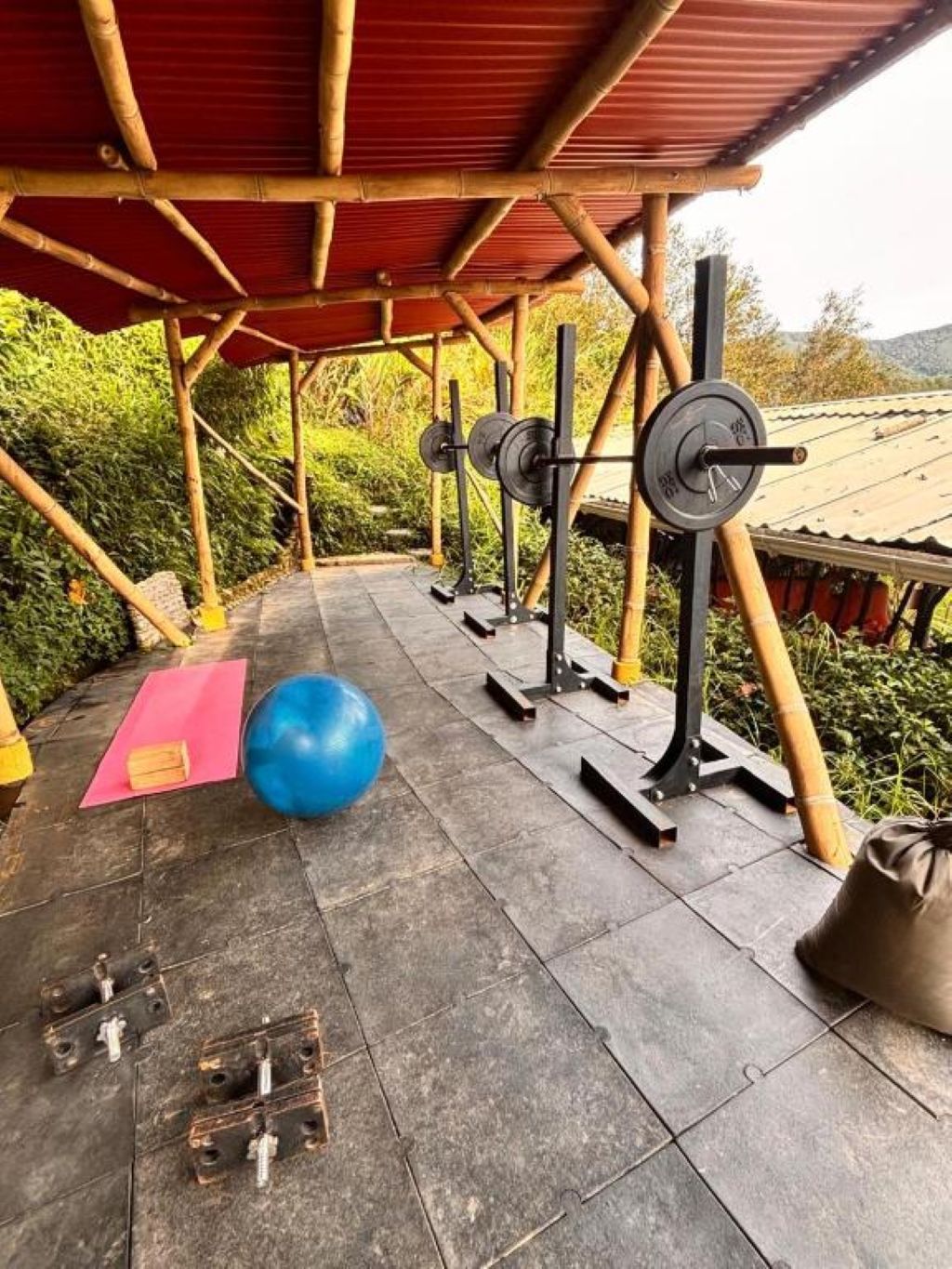 An outdoor gym area with exercise equipment, a blue exercise ball, and a yoga mat.