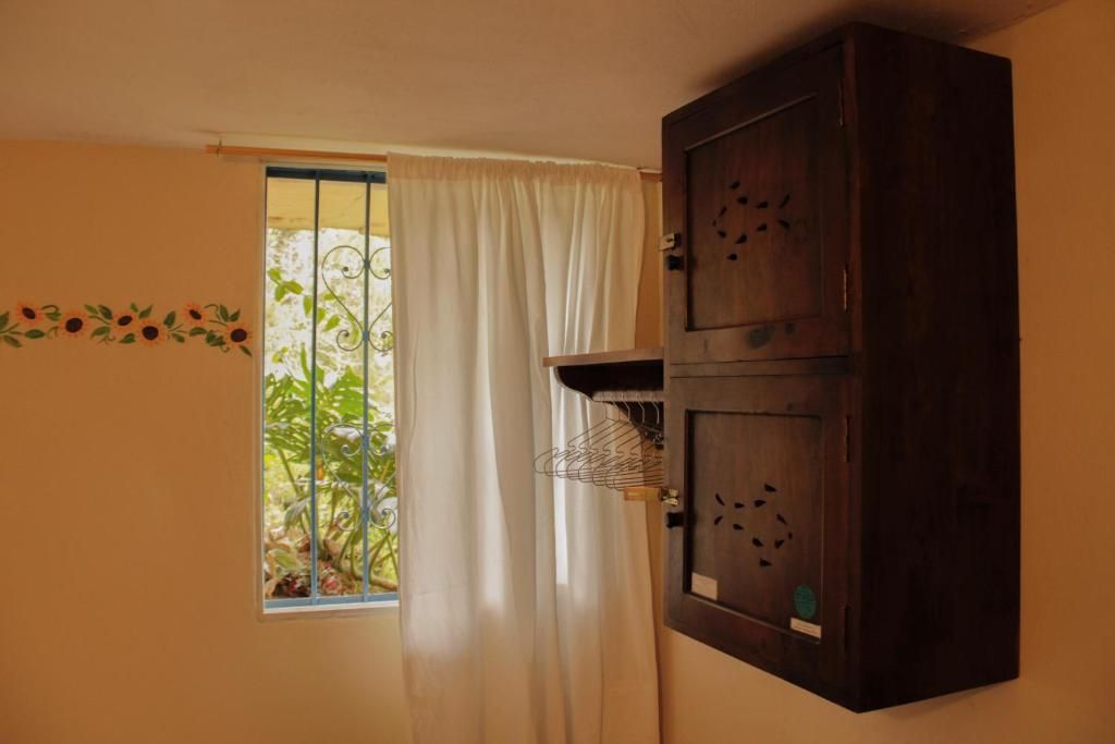 A room with a window, a curtain, a cabinet, and a wall decoration.