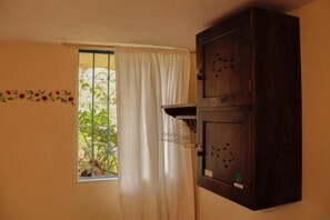 A room with a window, a curtain, a cabinet, and a wall decoration. - Girasol - Garden View (Guatapé)