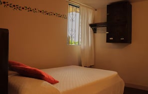 A room with a bed, a window with curtains, a wall-mounted shelf, and a decorative vine. - Girasol - Garden View (Guatapé)