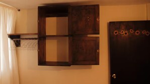 A room with a wooden cabinet, a coat rack, and a door with a sun motif. - Girasol - Garden View (Guatapé)