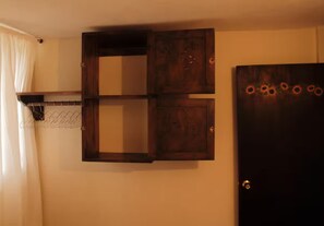 Une pièce comprenant un meuble en bois, un porte-manteau et une porte ornée d’un motif solaire.