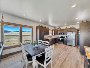 Una cocina moderna con comedor, ventanas amplias y vista a un campo.