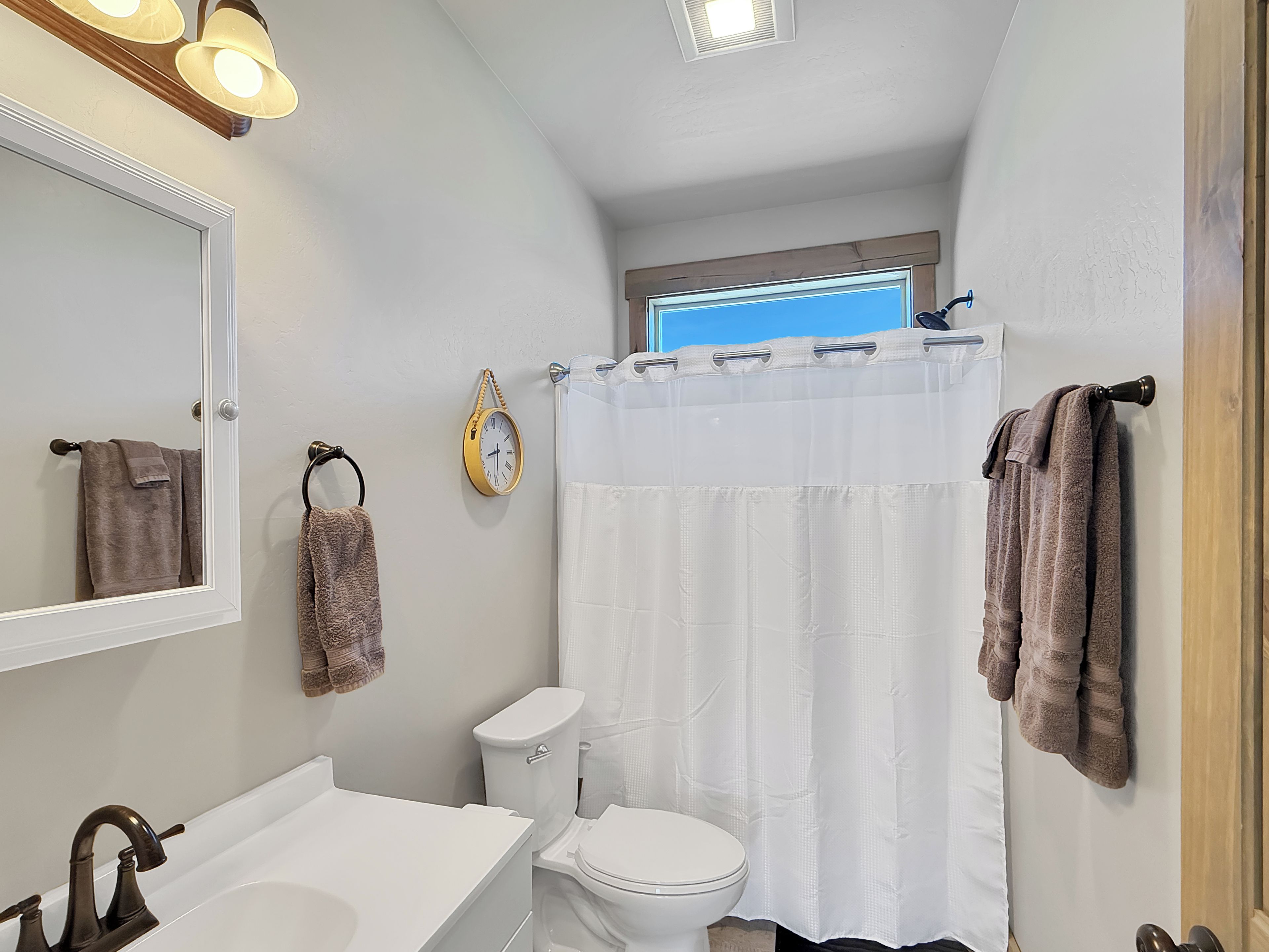 A bathroom with a white sink, a toilet, a shower curtain, and towels hanging on the wall.