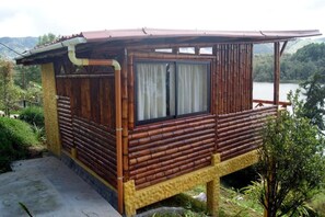 Una cabana de fusta amb una finestra gran, situada a la vora d'un cos d'aigua.