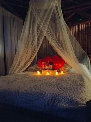 A bed with a canopy, candles, and heart-shaped decorations. - Papiro Guadua Deluxe - Cabin (Guatapé)