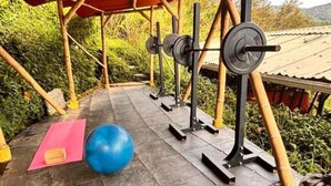 Ein Outdoor-Fitnessbereich mit Trainingsgeräten, einem blauen Übungsball und einer Yogamatte.