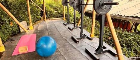Un espace de remise en forme en plein air équipé de matériel d’exercice, avec un ballon d’exercice bleu et un tapis de yoga.