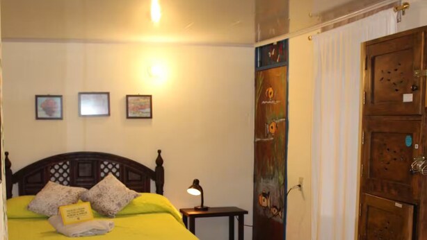 Ein Hotelzimmer mit zwei Betten, einem Nachttisch, einem Wandbild und einer Holztür.