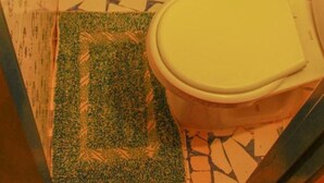 Ein Badezimmer mit Toilette, Dusche und einem gemusterten Boden.
