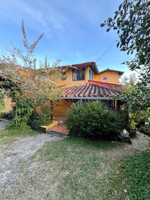 Une maison avec un toit en tuiles, un petit jardin et un chemin menant à l’entrée.