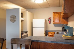 A kitchen with a refrigerator, stove, sink, and wooden cabinets.