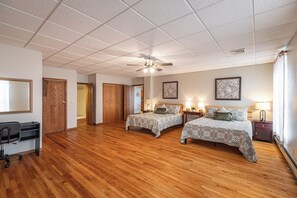 A hotel room with two beds, a desk, a chair, and a ceiling fan. - Stay and Play Downtown La Crosse Apartment! (La Crosse)